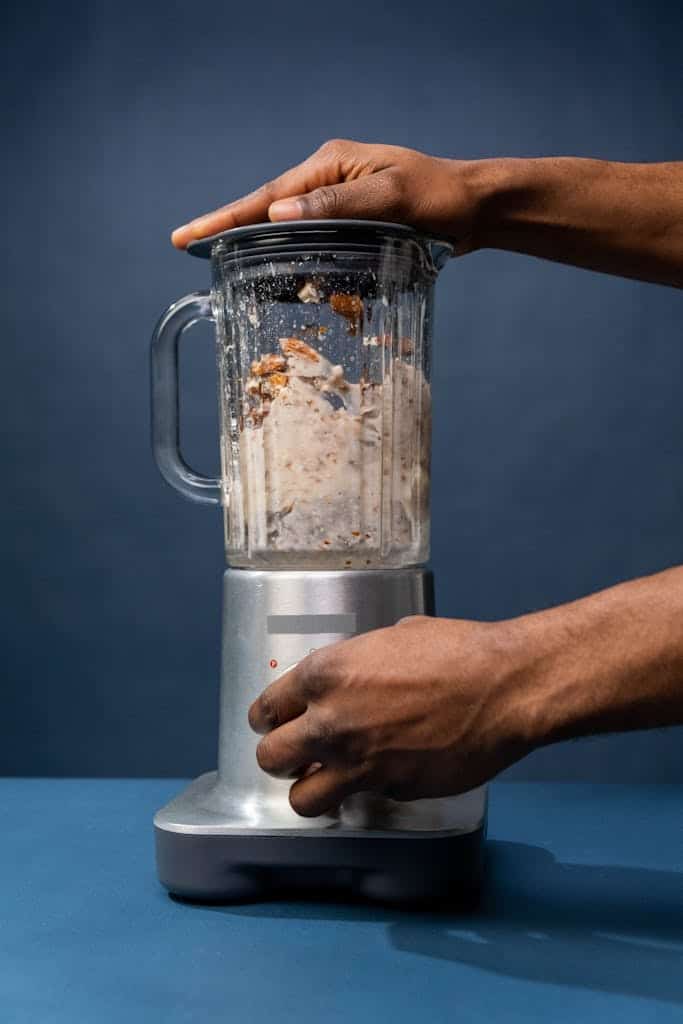 Close-up of hands preparing almond milk in a blender, showcasing a healthy lifestyle concept.